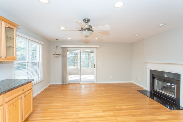 unfurnished living room with a glass covered fireplace, light wood finished floors, recessed lighting, and a wealth of natural light