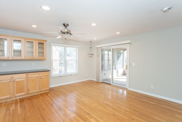 kitchen with light wood finished floors, recessed lighting, dark countertops, and baseboards