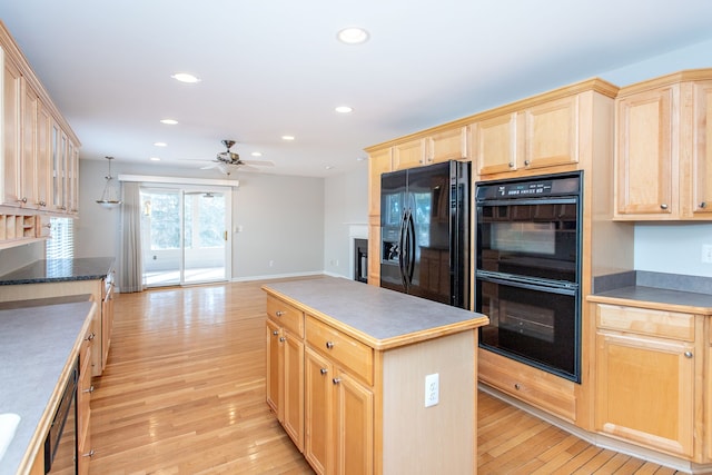 kitchen with light brown cabinets, light wood finished floors, recessed lighting, black appliances, and a glass covered fireplace