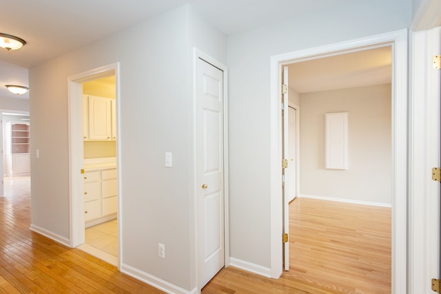 corridor with light wood finished floors and baseboards