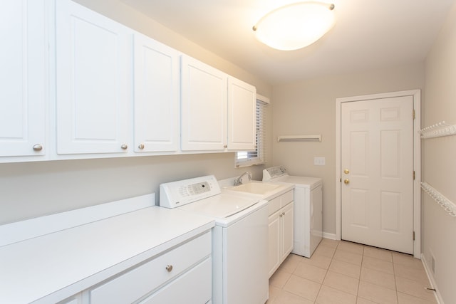 clothes washing area with baseboards, light tile patterned flooring, cabinet space, a sink, and independent washer and dryer