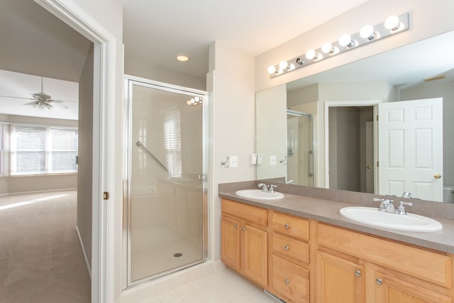 full bathroom with double vanity, a shower stall, a ceiling fan, and a sink