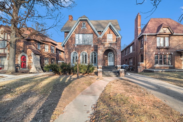 tudor house featuring brick siding and a chimney