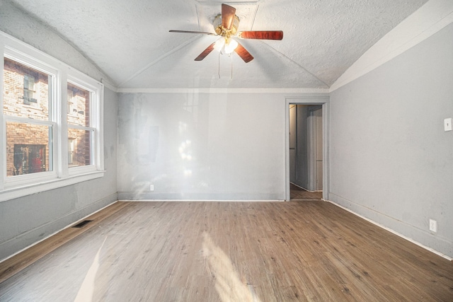 unfurnished room featuring a textured ceiling, wood finished floors, a ceiling fan, and vaulted ceiling