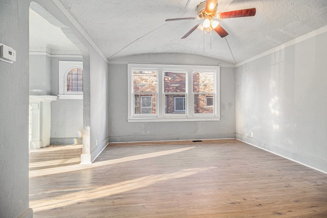 spare room with baseboards, wood finished floors, a ceiling fan, and vaulted ceiling