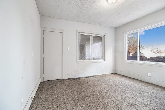 carpeted empty room with a textured ceiling