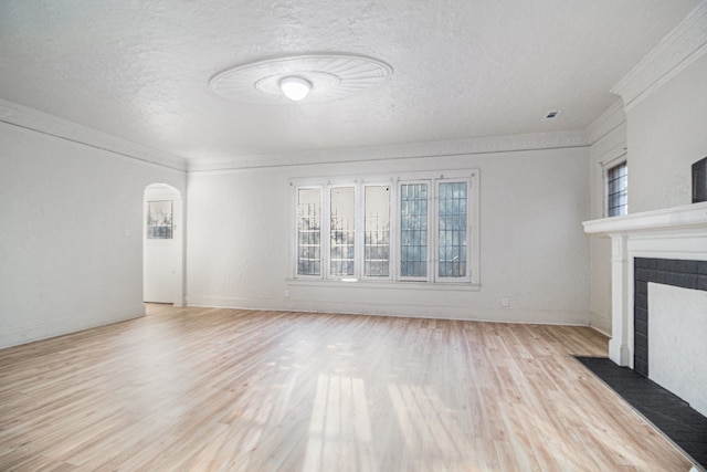 unfurnished living room with a wealth of natural light, a tile fireplace, and light wood-style floors