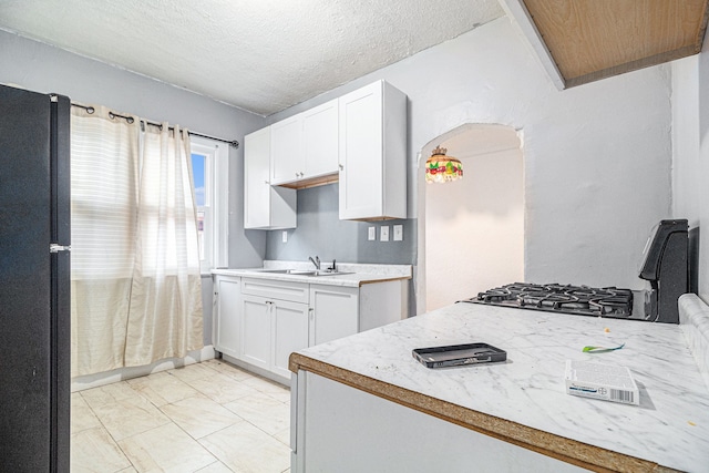 kitchen featuring a sink, white cabinets, light countertops, and freestanding refrigerator