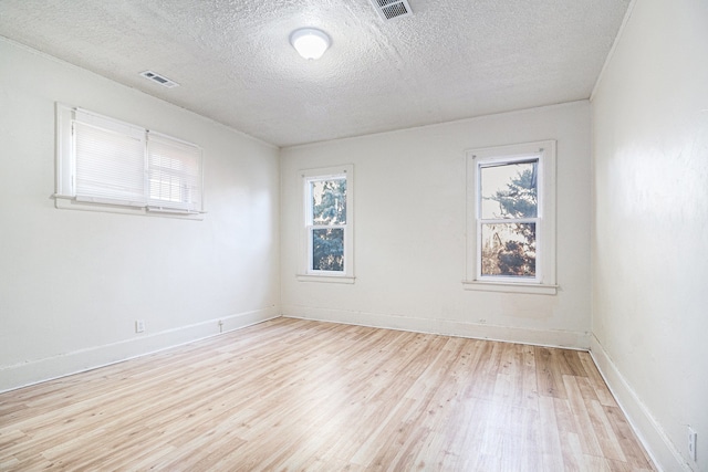 empty room with visible vents, plenty of natural light, and light wood finished floors