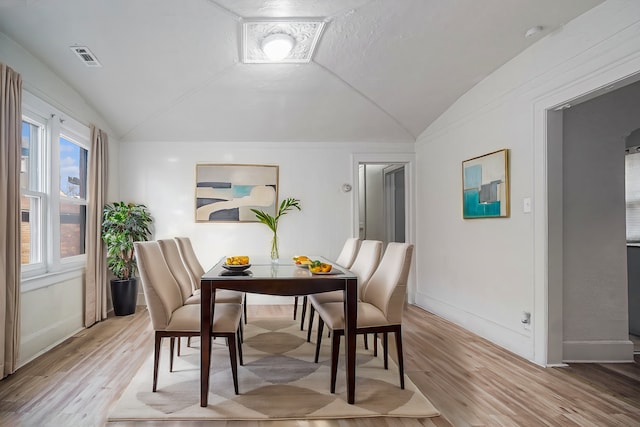 dining space featuring light wood-type flooring, baseboards, and vaulted ceiling