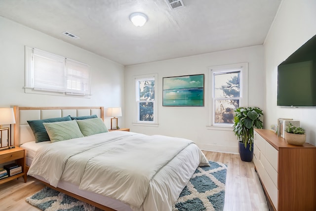 bedroom with visible vents, light wood-type flooring, and baseboards