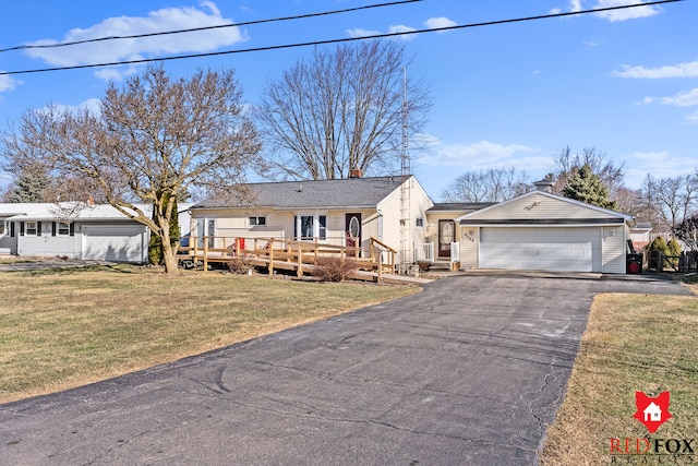 view of front of house with a deck, aphalt driveway, an attached garage, a front yard, and a chimney