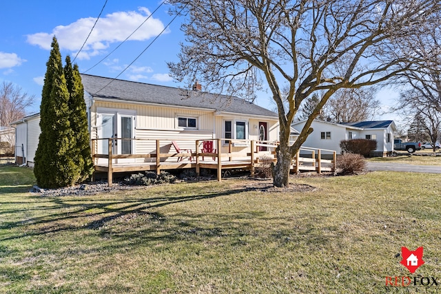 back of property with a wooden deck, a yard, and roof with shingles