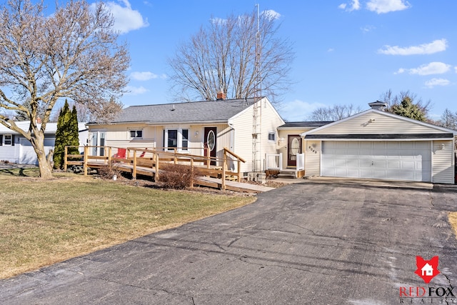 single story home featuring driveway, a wooden deck, a shingled roof, a chimney, and a front lawn