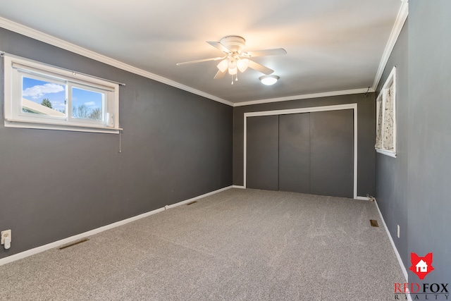 unfurnished bedroom with baseboards, visible vents, a closet, crown molding, and carpet flooring