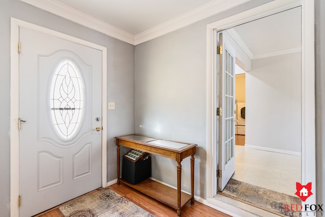 foyer featuring baseboards, wood finished floors, and ornamental molding