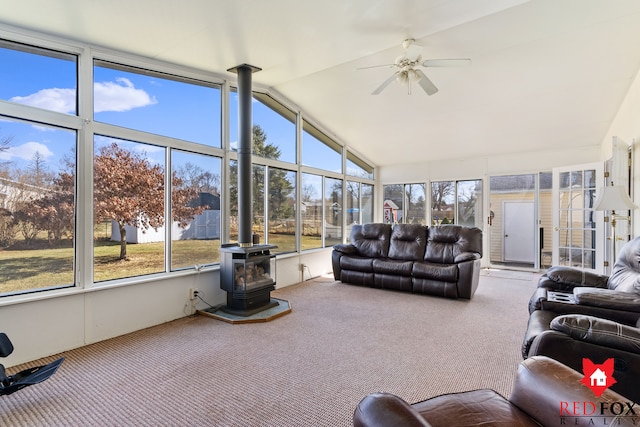 sunroom / solarium with vaulted ceiling, a wood stove, and a ceiling fan