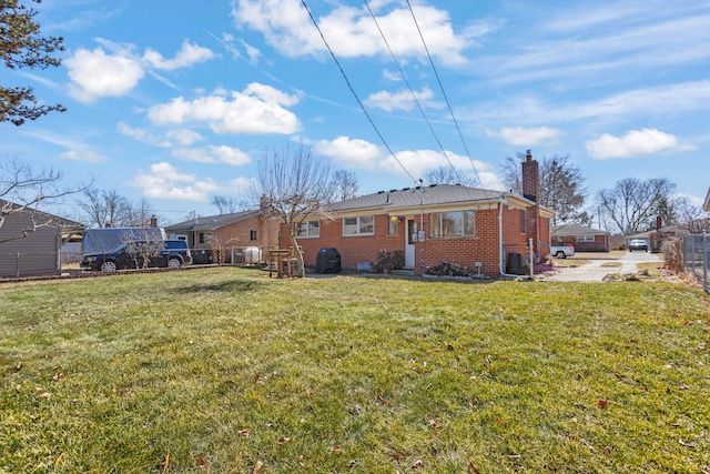 back of house with a yard, fence, brick siding, and a chimney