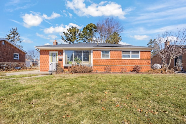 view of front of home with a front yard, brick siding, and a chimney