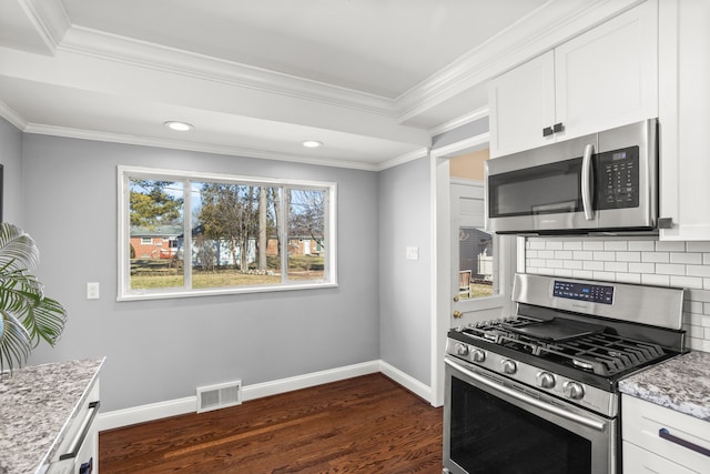 kitchen featuring visible vents, backsplash, dark wood-style floors, stainless steel appliances, and baseboards