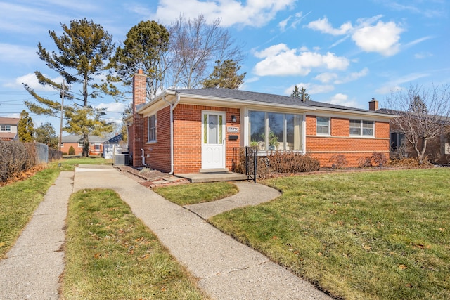 view of front facade with a front lawn, fence, brick siding, solar panels, and a chimney