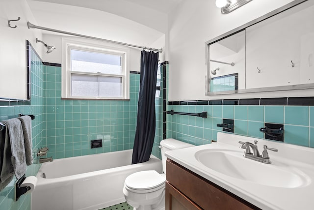 bathroom with toilet, tile walls, wainscoting, shower / bath combination with curtain, and vanity