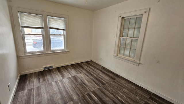 spare room featuring dark wood finished floors, baseboards, and visible vents