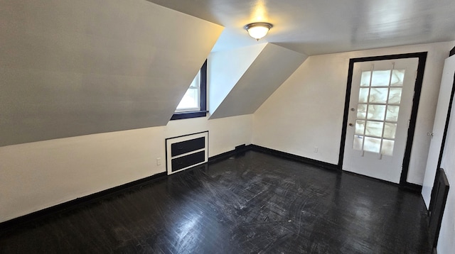 additional living space with dark wood finished floors, baseboards, and vaulted ceiling