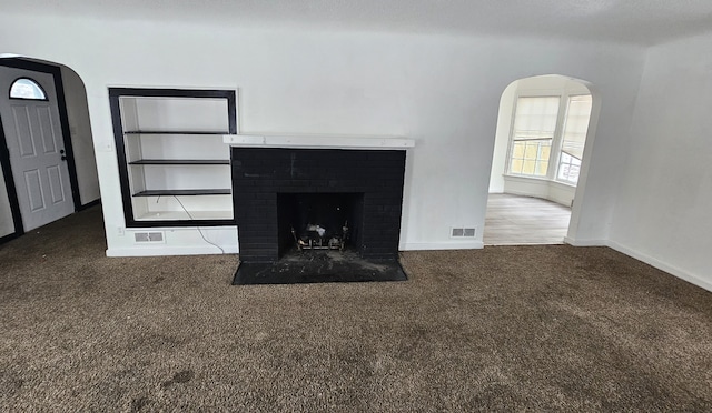 interior details featuring visible vents, baseboards, carpet flooring, a fireplace, and arched walkways