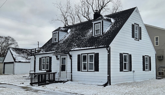 cape cod house featuring a garage, an outbuilding, and a chimney