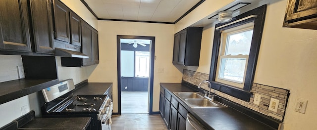 kitchen with a ceiling fan, a sink, under cabinet range hood, dark countertops, and stainless steel range with electric cooktop