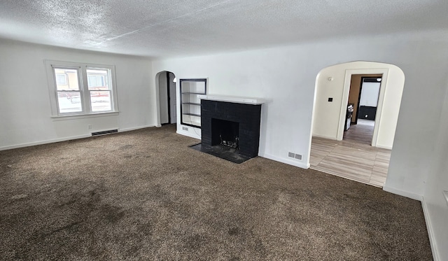 unfurnished living room featuring arched walkways, visible vents, and carpet floors