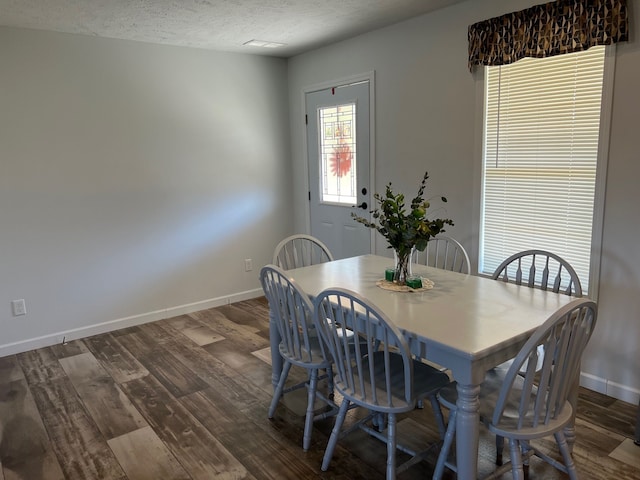 dining space with dark wood-style floors, baseboards, and a textured ceiling