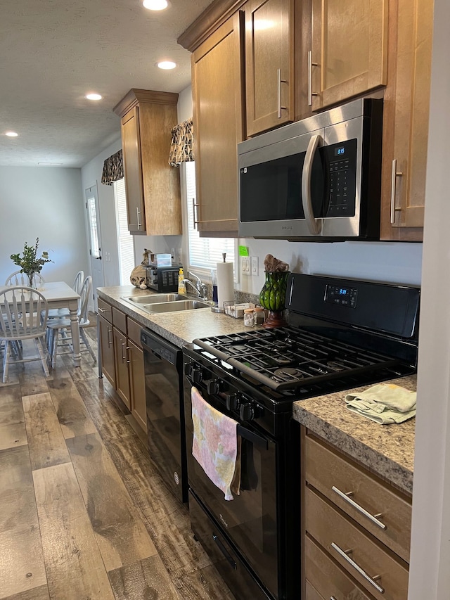 kitchen featuring dark wood-type flooring, light countertops, recessed lighting, black appliances, and a sink