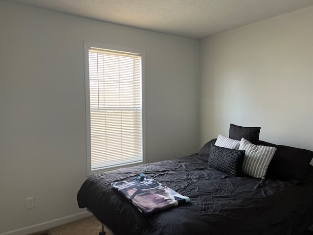 bedroom with baseboards, carpet floors, and a textured ceiling