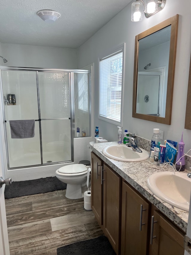 bathroom featuring a sink, visible vents, a shower with shower door, and wood finished floors