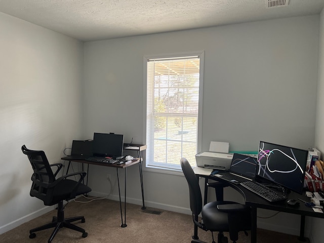 carpeted office space with visible vents, baseboards, and a textured ceiling