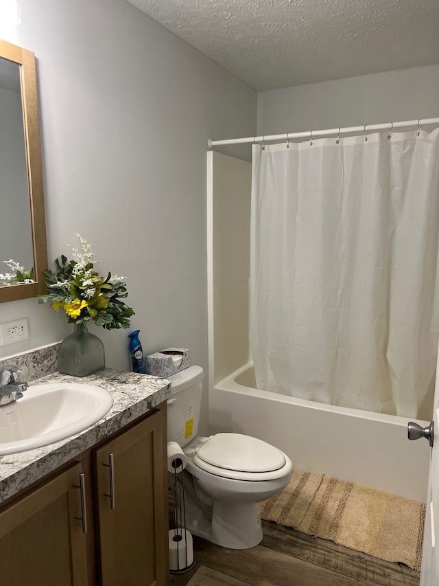 bathroom with toilet, a textured ceiling, wood finished floors, shower / bath combination with curtain, and vanity