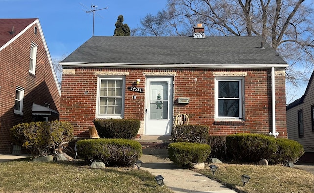 view of front of house with brick siding and a shingled roof