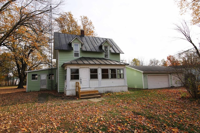 back of house with a standing seam roof, a garage, a chimney, and metal roof