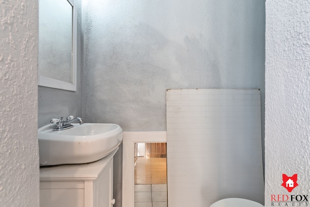 bathroom featuring toilet, vanity, and a textured wall