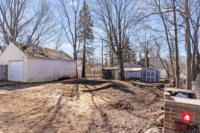 view of yard with a detached garage, an outdoor structure, and a shed