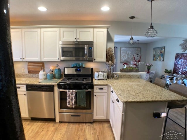 kitchen featuring recessed lighting, light wood-style flooring, a peninsula, white cabinets, and stainless steel appliances