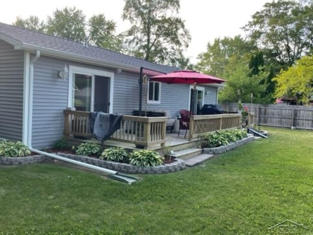 rear view of house featuring a yard, a wooden deck, and fence