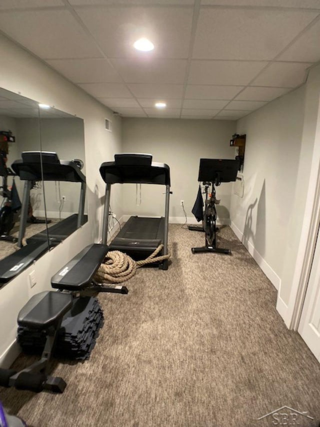 exercise room featuring a paneled ceiling, baseboards, and carpet flooring