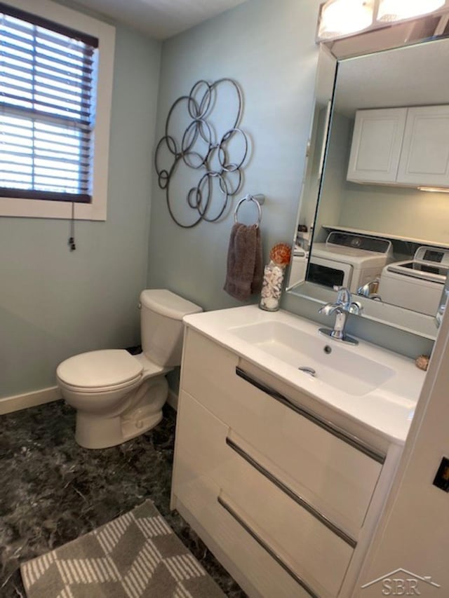 half bathroom with toilet, washing machine and dryer, and vanity