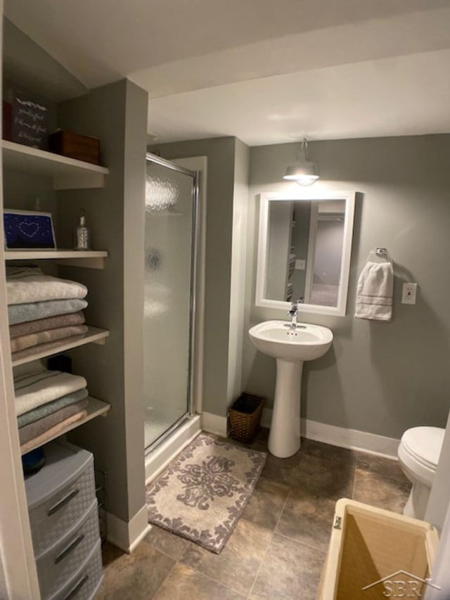 bathroom featuring a shower stall, toilet, and baseboards