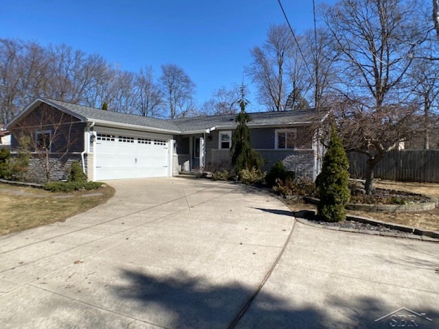 ranch-style house with brick siding, an attached garage, concrete driveway, and fence