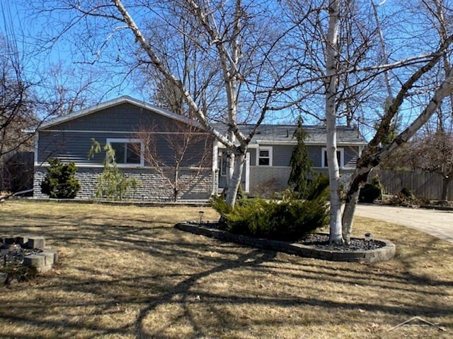 exterior space with brick siding, a lawn, concrete driveway, and fence