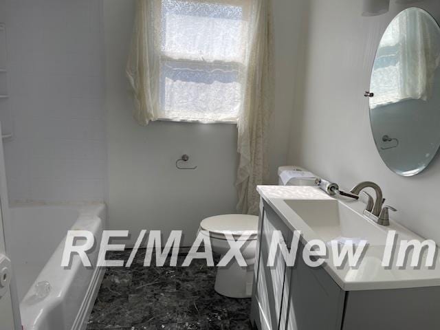 bathroom featuring toilet, a tub to relax in, and vanity